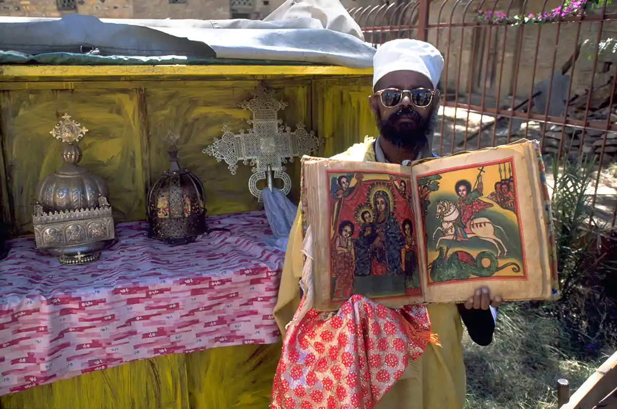 Ethiopian Orthodox priest with ancient Bible and crowns of Ethiopian kings, St. Mary of Zion, Axum Ethiopian Orthodox priest with ancient Bible and crowns of Ethiopian kings, St. Mary of Zion, Axum