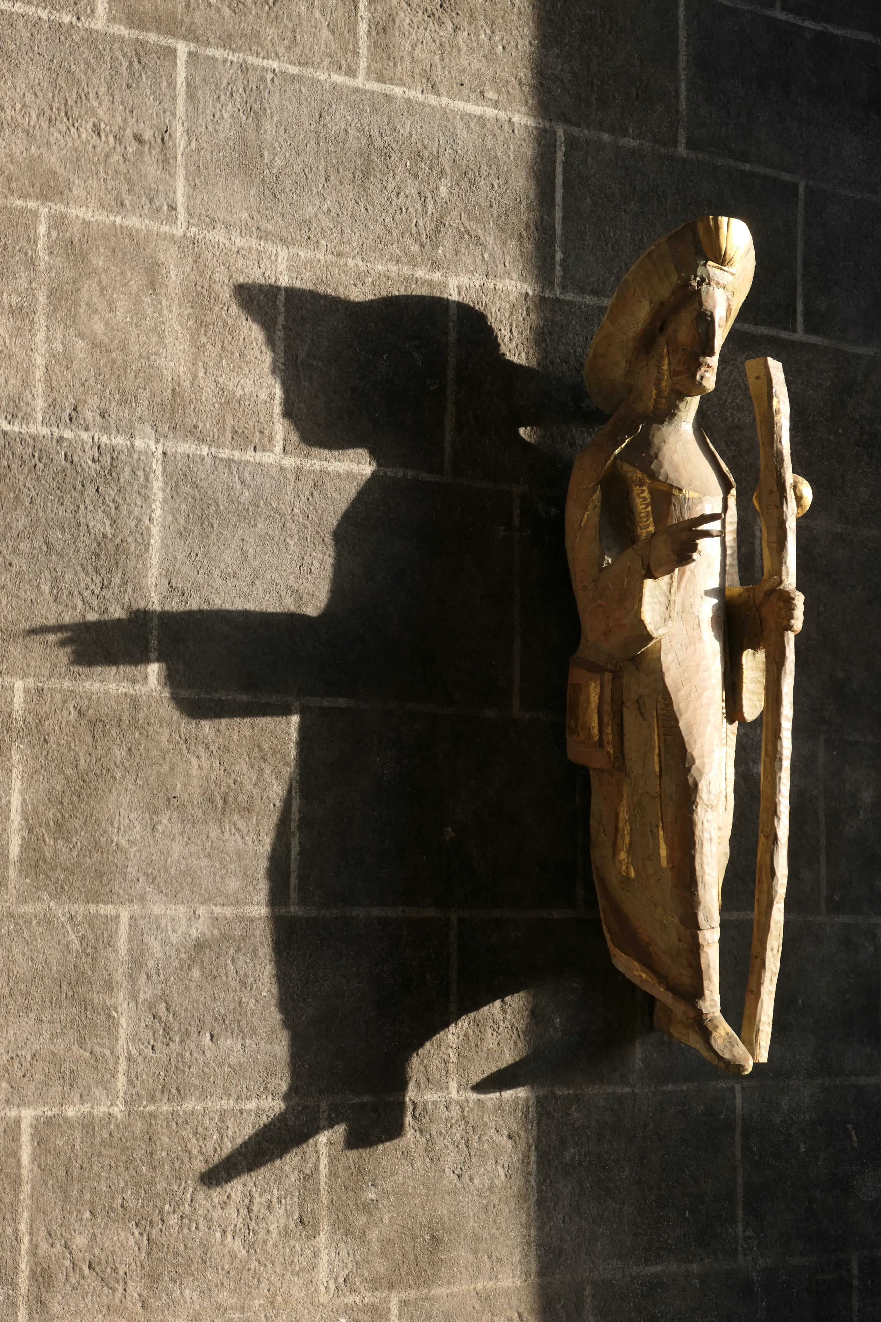 Wooden statue and its shadow of St. James pointing towards Santiago de Compostela, Spain. On outside entrance of Cathedral of Notre Dame, Le Puy Wooden statue and its shadow of St. James pointing towards Santiago de Compostela, Spain. On outside entrance of Cathedral of Notre Dame, Le Puy